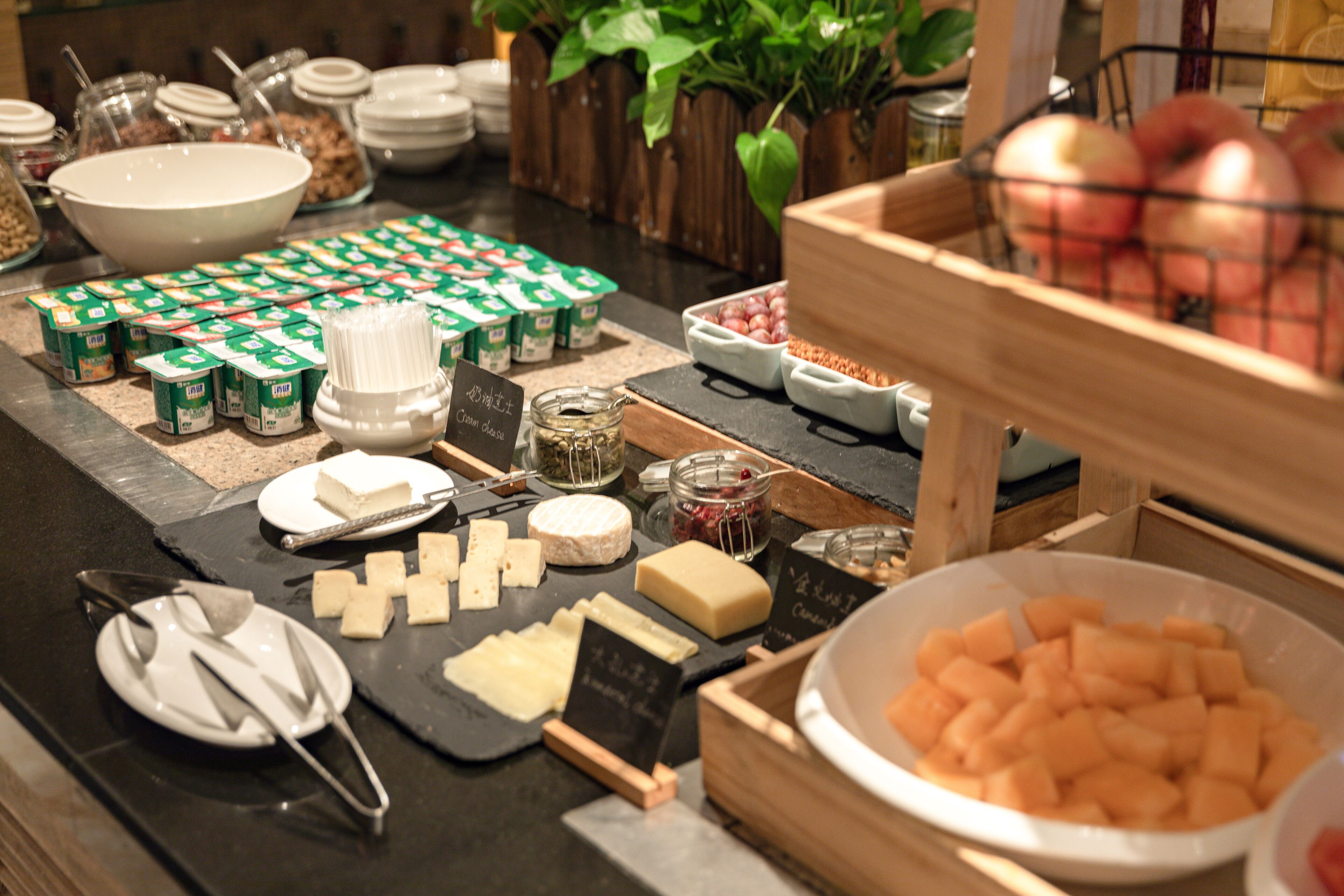 Un buffet proposant une variété d’aliments, notamment du fromage, des fruits et des yaourts.