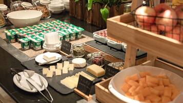 Un buffet proposant une variété d’aliments, notamment du fromage, des fruits et des yaourts.