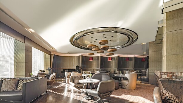 Una sala de estar moderna con una lámpara de techo redonda, una zona de comedor con una mesa circular y un conjunto de sofás.