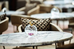 A marble table with a glass dome containing a flower and a gold ornament.