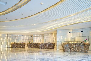 Un hall moderno con piso de mármol, una recepción y un diseño de techo único.