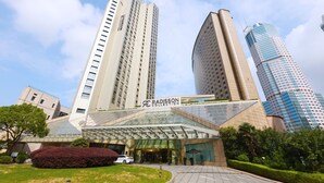 A modern hotel with a glass facade, a prominent Radisson Collection sign, and a surrounding urban landscape with other high-rise buildings. - Radisson Collection Yangtze Shanghai (Shanghai)