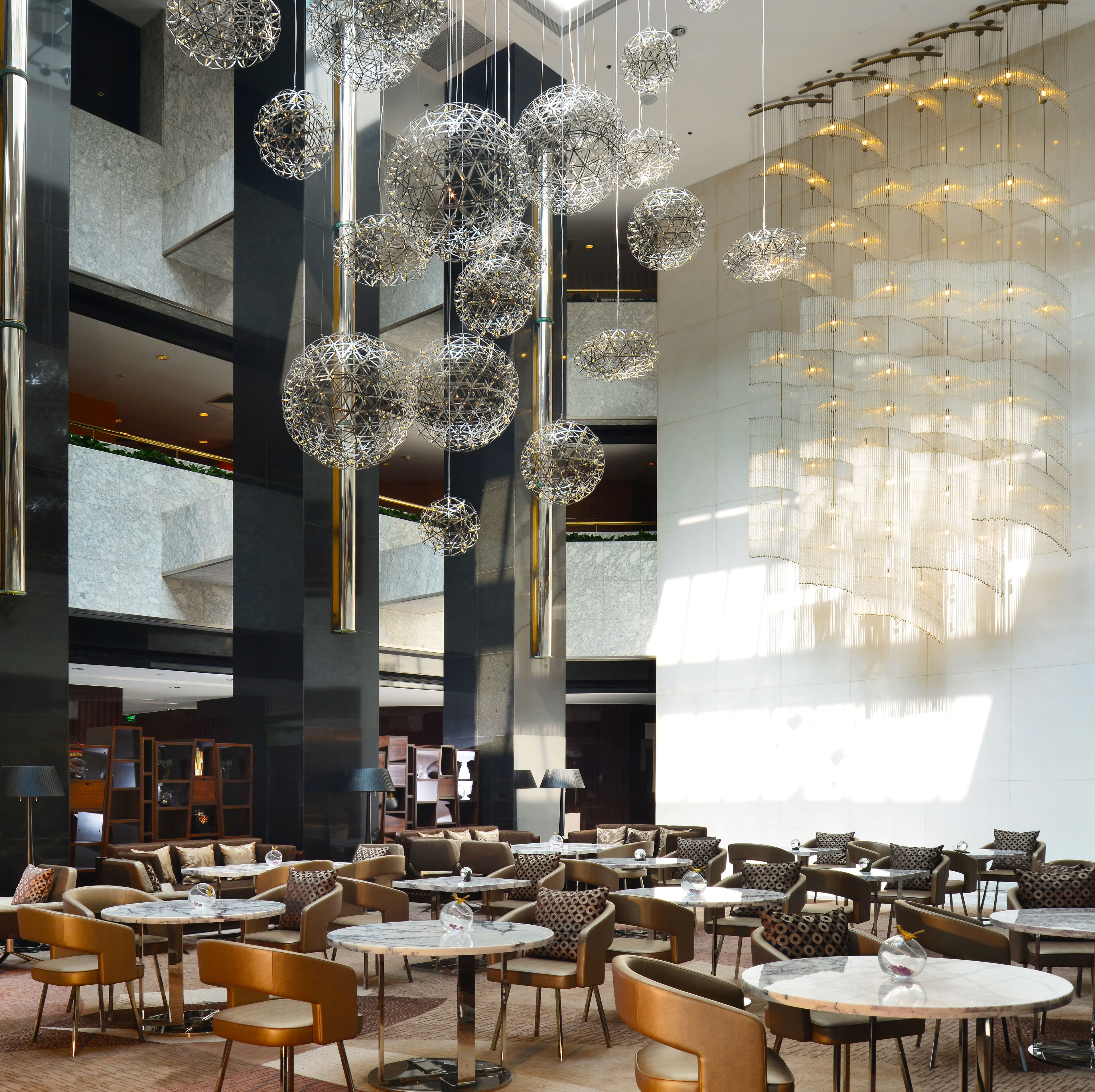A modern interior with hanging spherical light fixtures and a seating area with round tables and chairs.