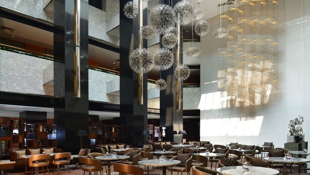 A spacious hotel lobby with multiple seating areas, including round tables and sofas, and a large chandelier with spherical light fixtures. - Radisson Collection Yangtze Shanghai (Shanghai)