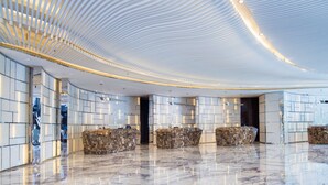 A modern lobby with a curved ceiling, marble flooring, and seating areas with patterned upholstery. - Radisson Collection Yangtze Shanghai (Shanghai)