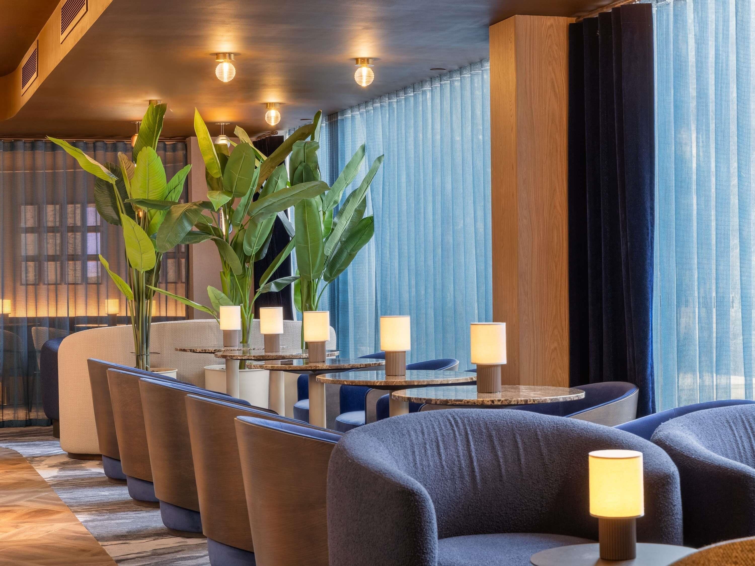 Un espace de détente moderne, doté de sièges, de tables et d’un éclairage d’ambiance.