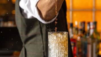 A bartender pouring a drink into a glass with ice.
