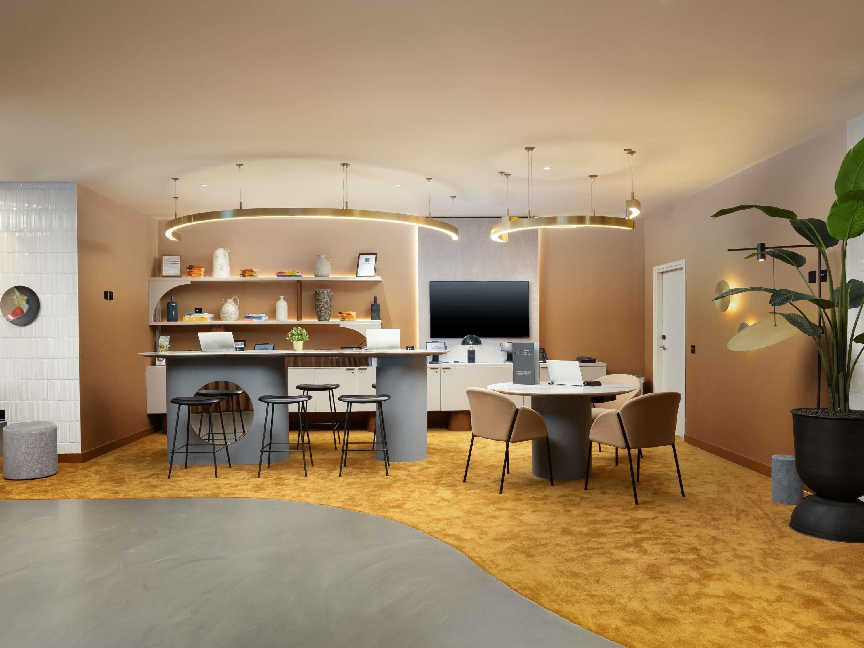 A modern kitchen with a central island, bar stools, a dining table, and pendant lighting.