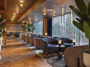 A hotel lobby with seating areas, a patterned floor, and large windows. - ibis London Earls Court (London)