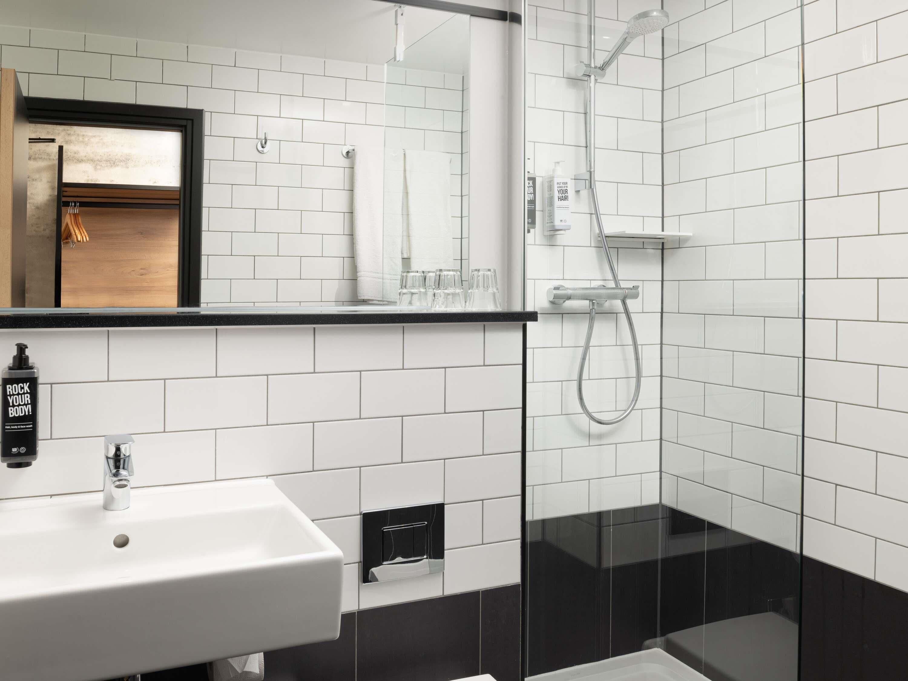 A modern bathroom with a white sink, a glass shower enclosure, and a mirror above the sink.