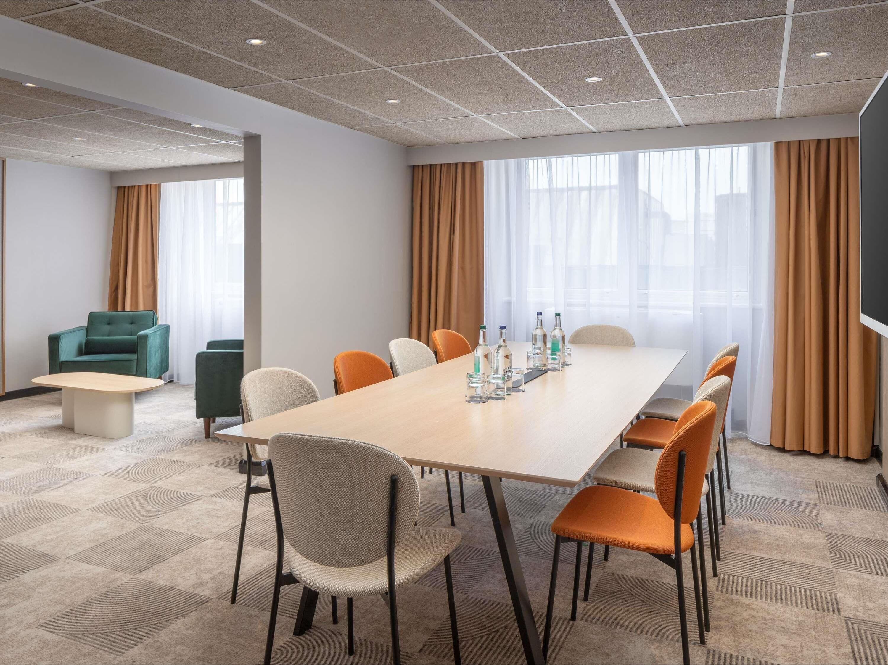 Une salle de conférence avec une longue table, de nombreuses chaises et un écran de télévision.