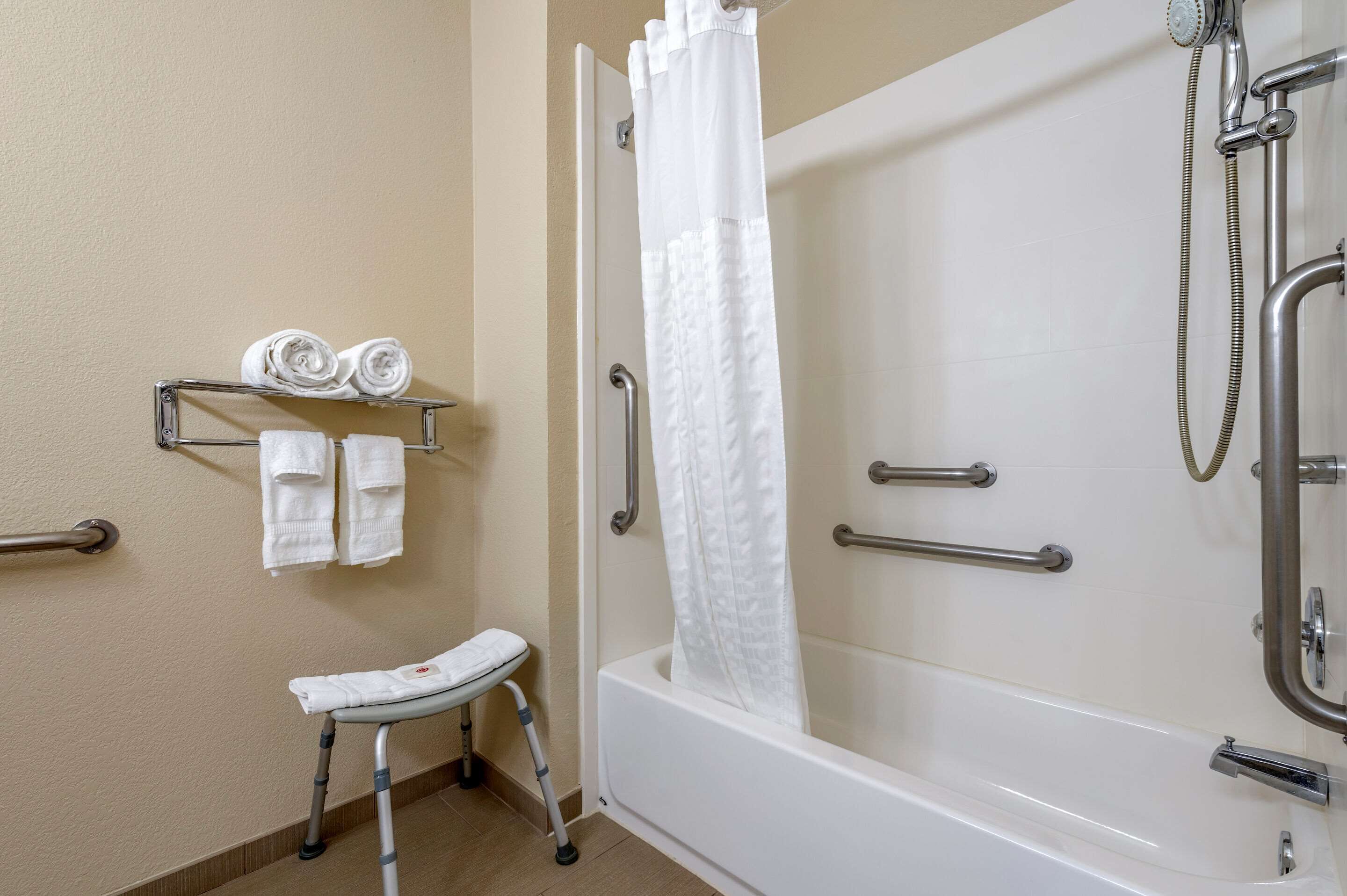 A bathroom with a bathtub, shower, and a wheelchair-accessible bench.