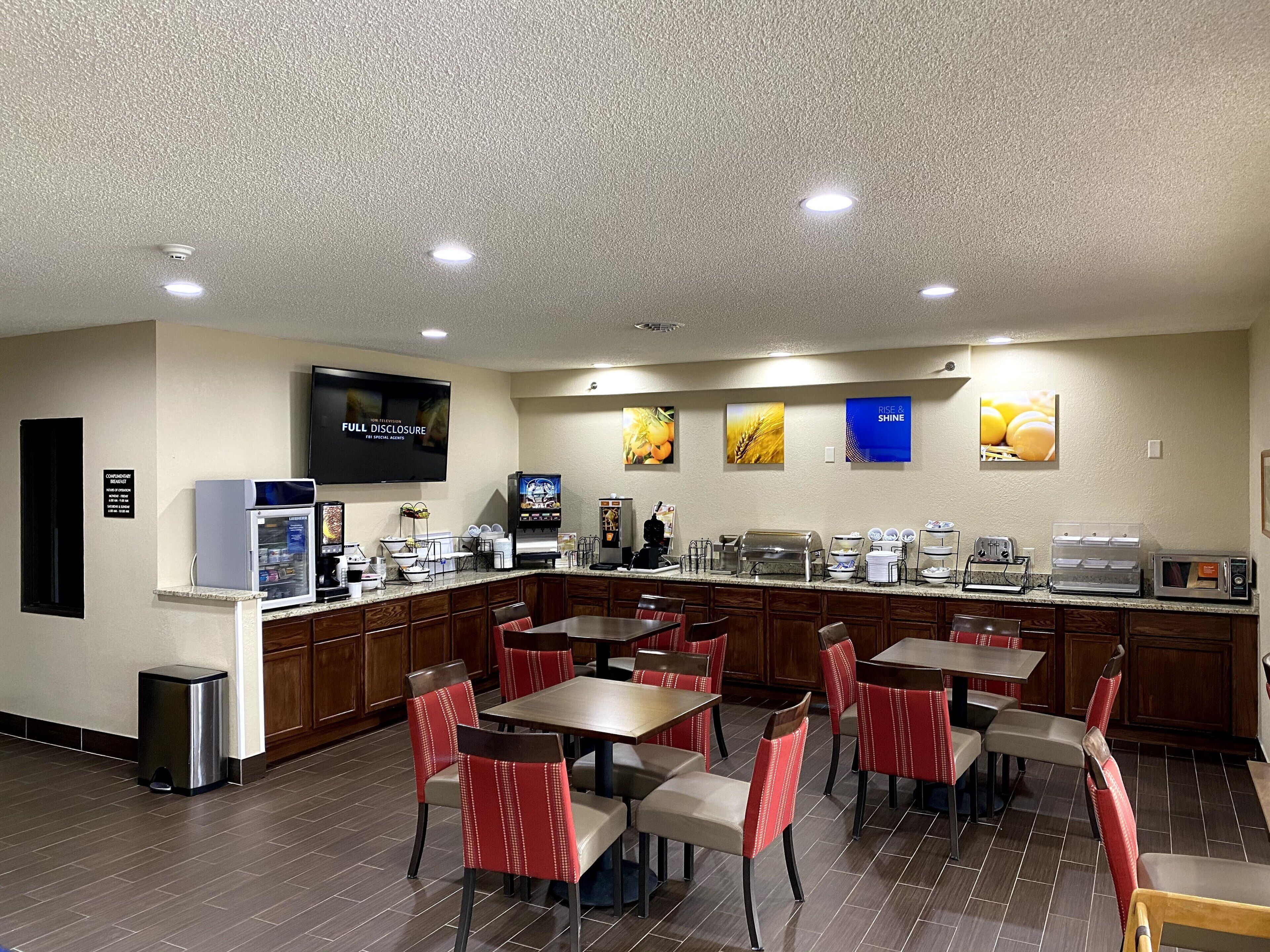 Een hotelkamer met een kitchenette, een flatscreen-tv, een koffiezetapparaat en een ontbijtbalk.