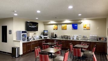 Een hotelkamer met een kitchenette, een flatscreen-tv, een koffiezetapparaat en een ontbijtbalk.