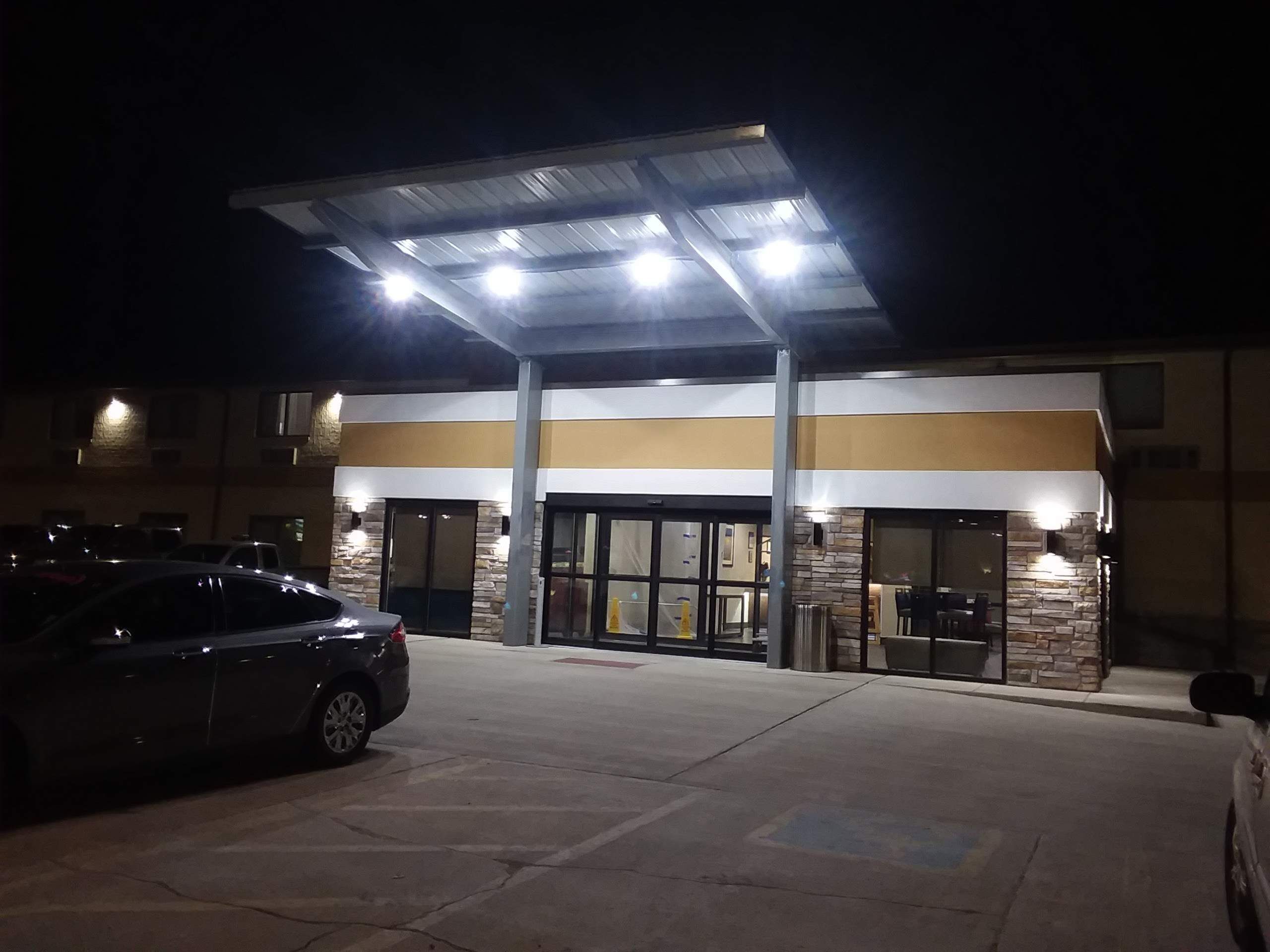 A building with a covered entrance, stone facade, and a parking lot.