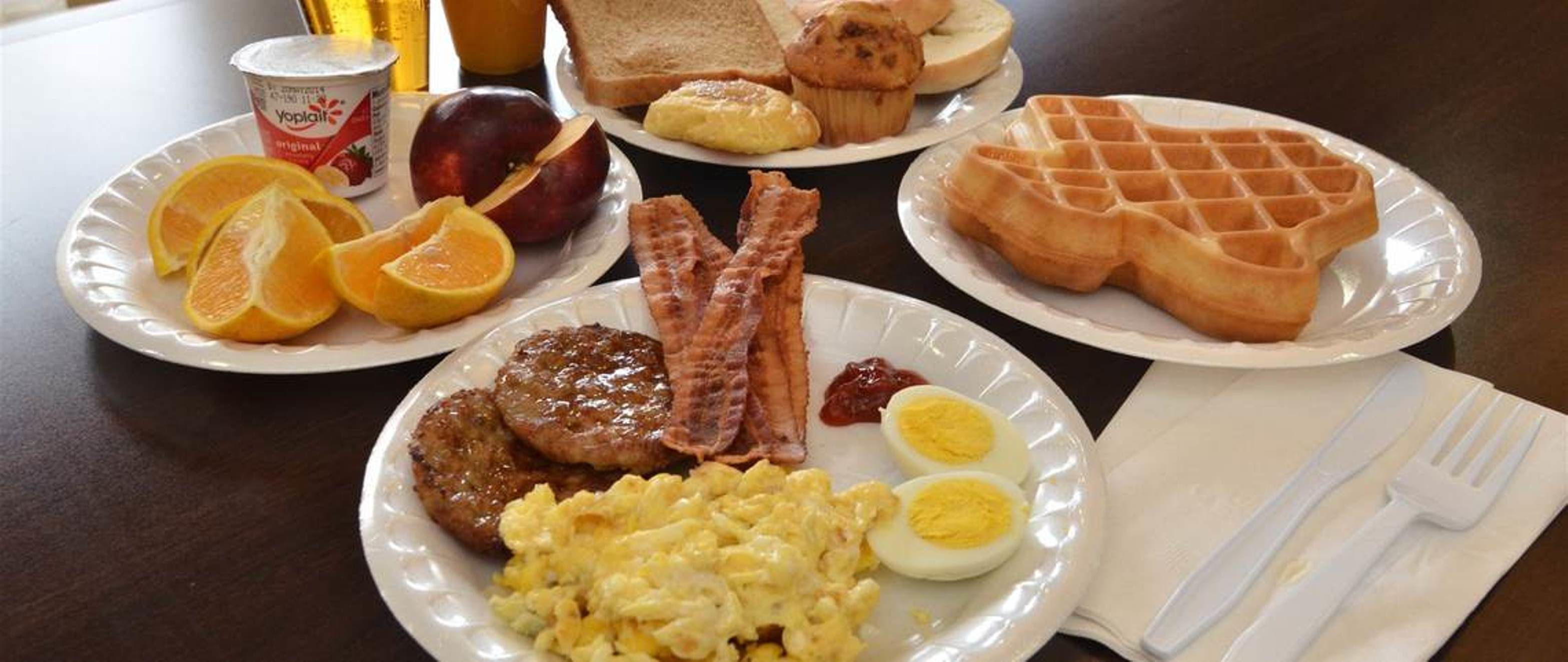 A breakfast plate with eggs, bacon, sausage, toast, and orange slices.