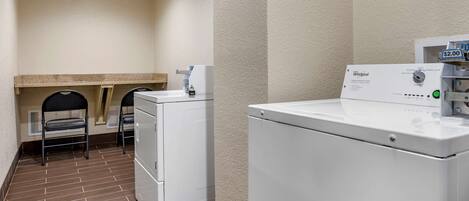 A laundry room with a Whirlpool washer and dryer, a small sink, and a chair.