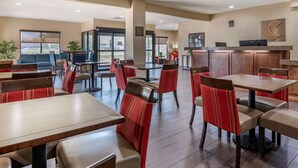 A spacious indoor area with multiple seating arrangements including tables and chairs, a reception desk, and a view through large windows. - Comfort Inn Near Kokomo Speedway (Kokomo)