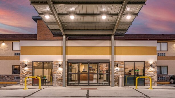 A hotel entrance with a covered walkway, glass doors, and a parking area. - Comfort Inn Near Kokomo Speedway (Kokomo)