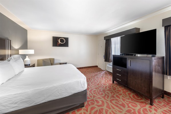 A hotel room with a large bed, a flat-screen TV, a dresser, and a wall-mounted artwork.