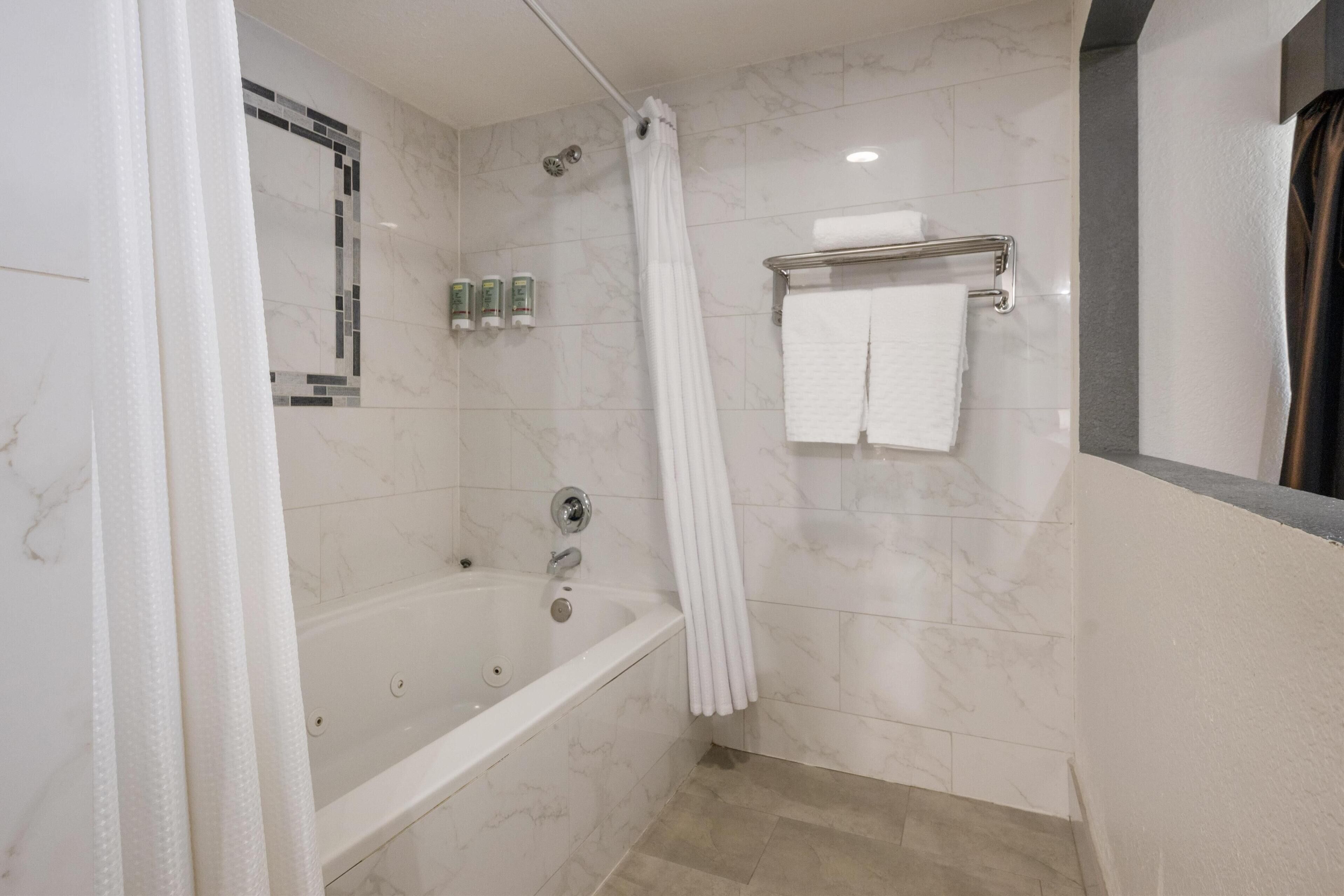 A modern bathroom with a bathtub, a shower curtain, and a towel rack.