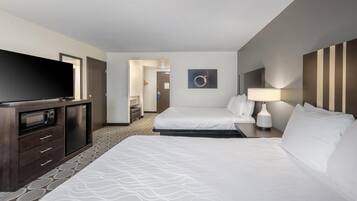 A hotel room with two beds, a TV, a desk with a lamp, and a microwave.