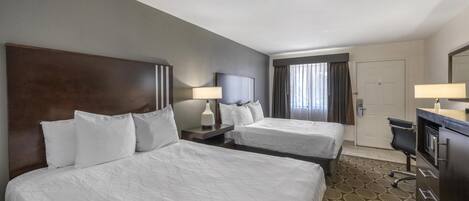 Ein Hotelzimmer mit zwei Betten, einem Schreibtisch, einem Stuhl, einer Kommode und einer Tür.