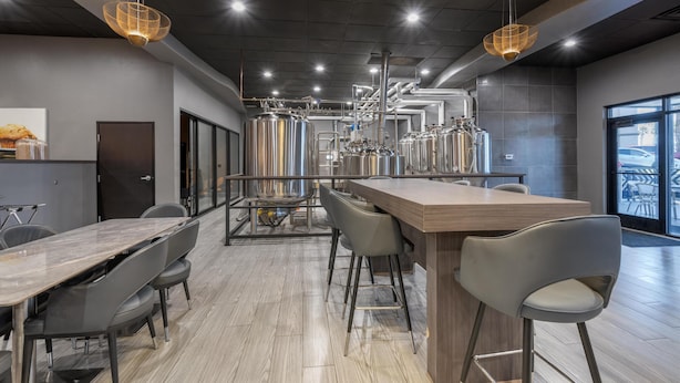 Una cocina moderna con electrodomésticos de acero inoxidable, una encimera de madera larga y taburetes de bar.