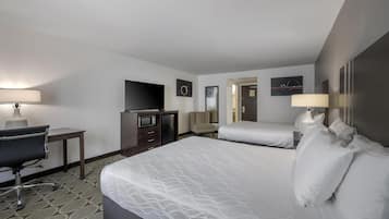 Una habitación de hotel con dos camas, un escritorio, una silla, un televisor y una lámpara.