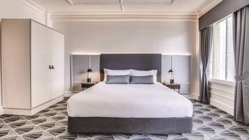 A modern hotel room with a large bed, geometric patterned floor, and a wardrobe.