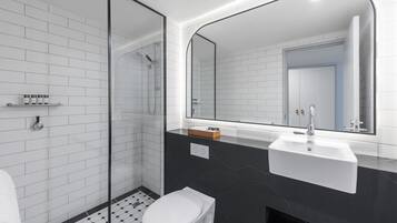 Un baño moderno con ducha de vidrio, inodoro blanco y lavamanos de mármol negro.