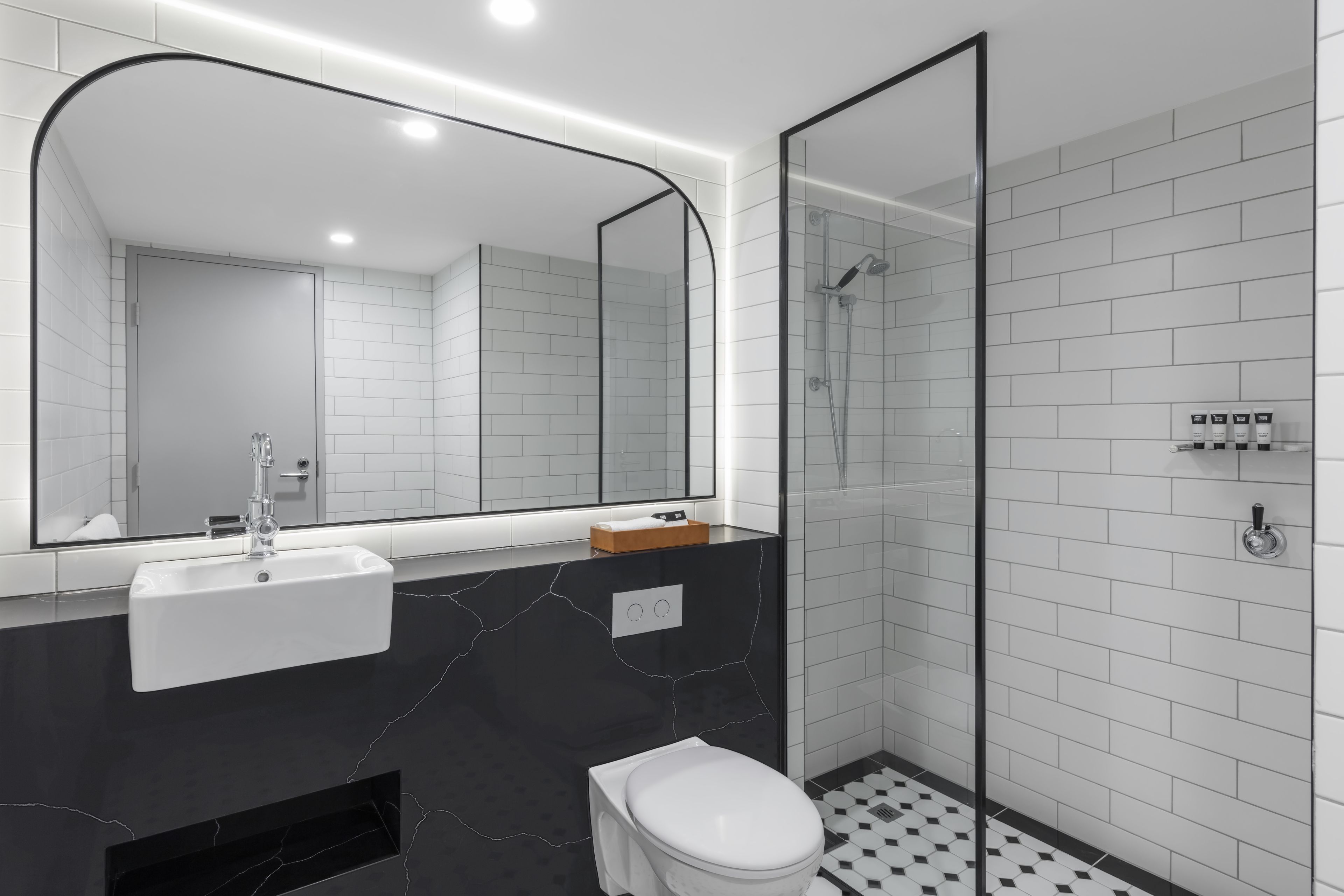 A modern bathroom with a white sink, a toilet, and a glass-enclosed shower.