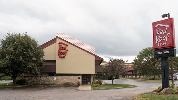 Ein Red Roof Inn mit Steinverkleidung, einem einladenden Schild und einem Parkplatz.