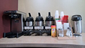 Ein Kaffeeangebot mit verschiedenen Kaffeeautomaten, Einwegbechern und einem Sahnespender.