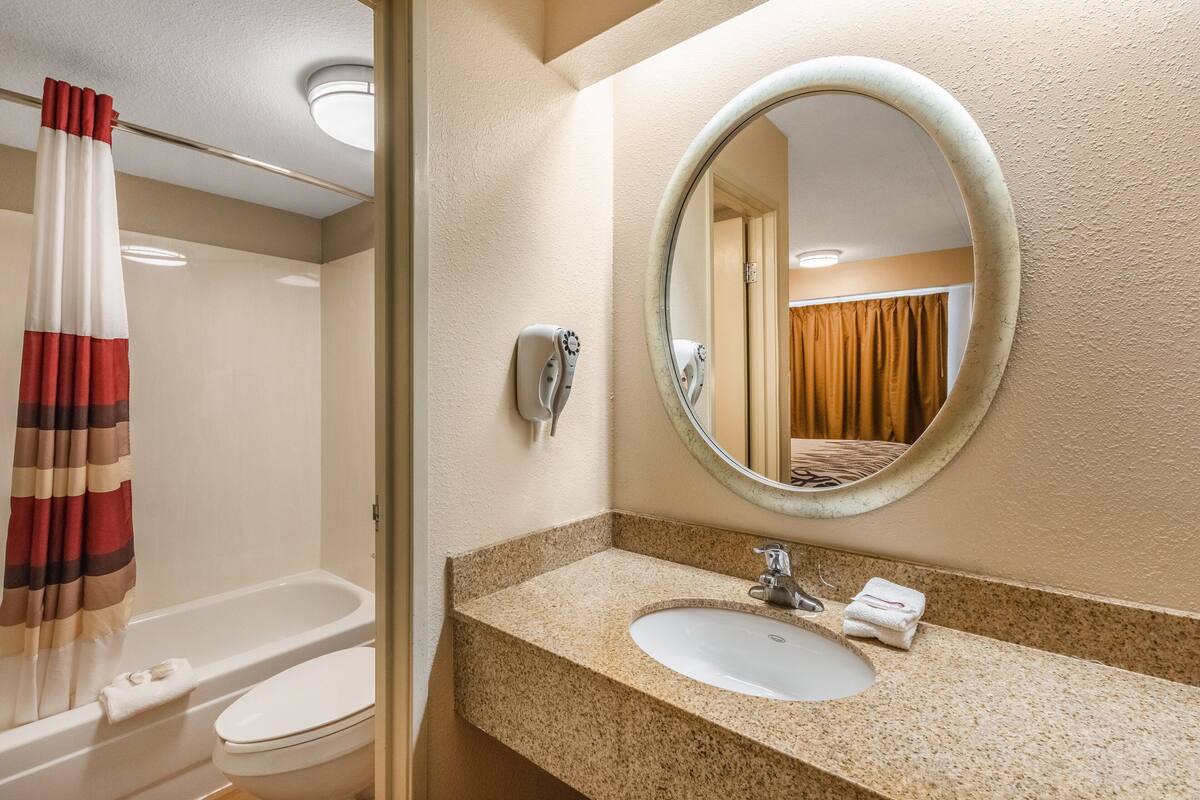 Ein Badezimmer mit einer weißen Badewanne, einem Waschbecken mit Spiegel und einem Handtuchhalter.