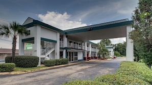 A hotel with a covered parking area, a staircase leading to the entrance, and a sign indicating the presence of a Candace establishment. - Key West Inn - Montgomery (Montgomery)