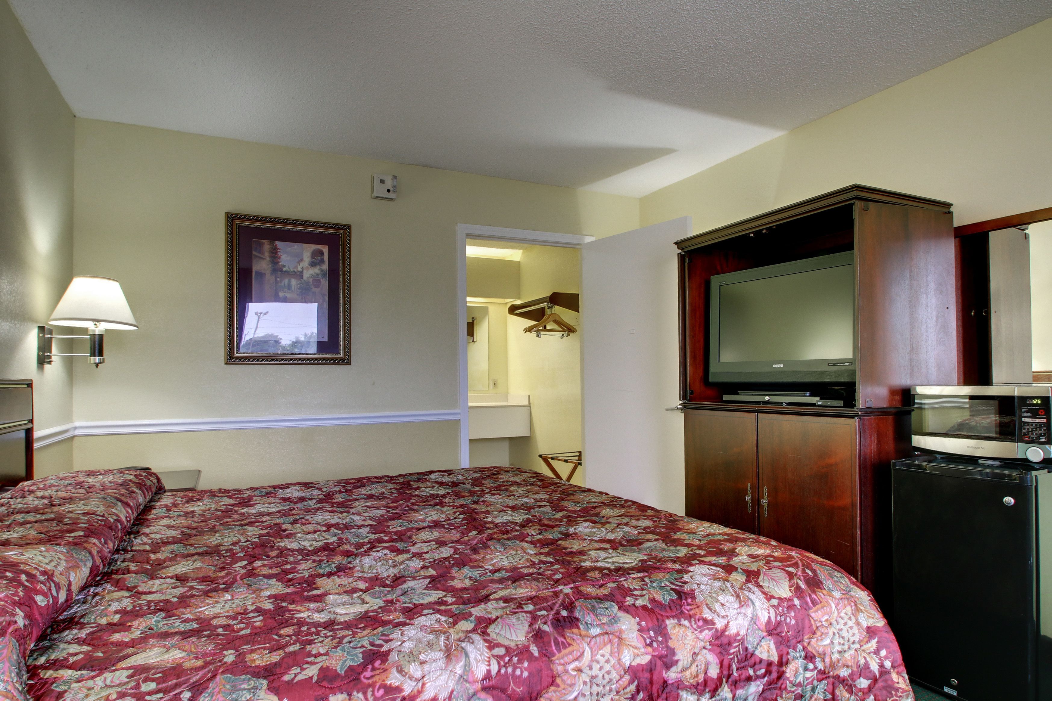 A hotel room with a bed, a television, a microwave, and a wardrobe.