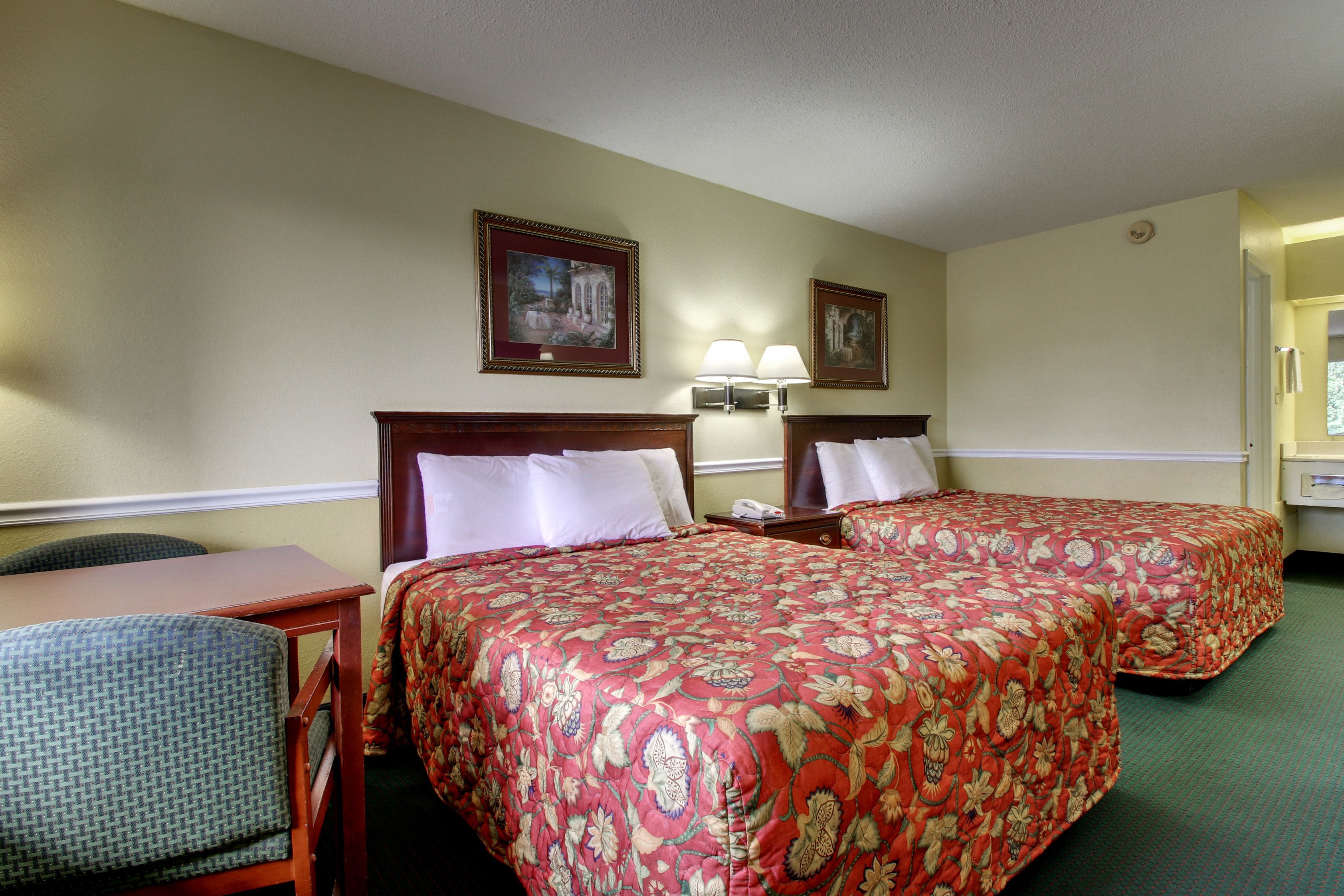 A hotel room with two beds, a desk, and a chair.