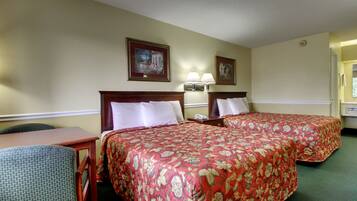 A hotel room with two beds, a desk, and a chair.
