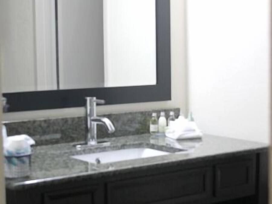 A bathroom with a large mirror, a sink, and a dark vanity.