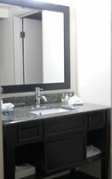 A bathroom with a large mirror, a sink, and a dark vanity.