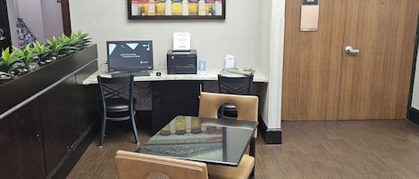 Zona de recepción con mostrador, computadora, impresora y área de descanso con sillas.