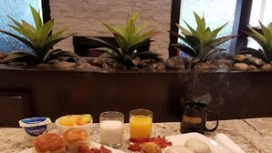 A breakfast buffet with plates of eggs, bacon, pastries, and juice. - Club - Hotel Nashville Inn & Suites (Nashville)