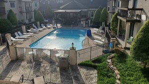 A swimming pool with lounge chairs and a covered area, surrounded by buildings and greenery. - Club - Hotel Nashville Inn & Suites (Nashville)
