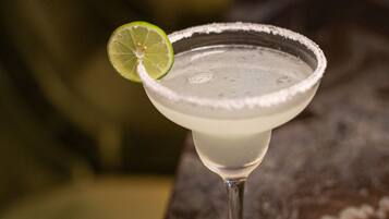A margarita cocktail with a lime garnish on a bar counter.
