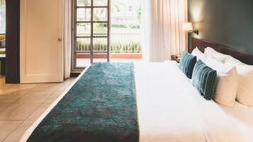 Una camera d'albergo con un letto, un comodino, una lampada e vista sull'esterno attraverso una finestra.