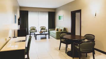 Habitación de hotel con comedor, sofá, televisor y puerta.