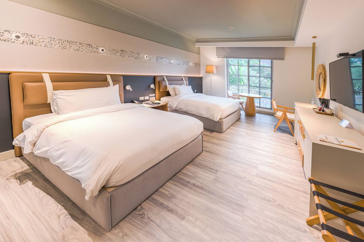 Ett modernt hotellrum med två sängar, ett skrivbord och en TV.