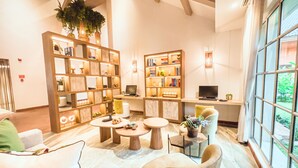 A modern lobby with a large bookshelf, comfortable seating, and a large window with a view of greenery. - Oro Verde Machala (Machala)