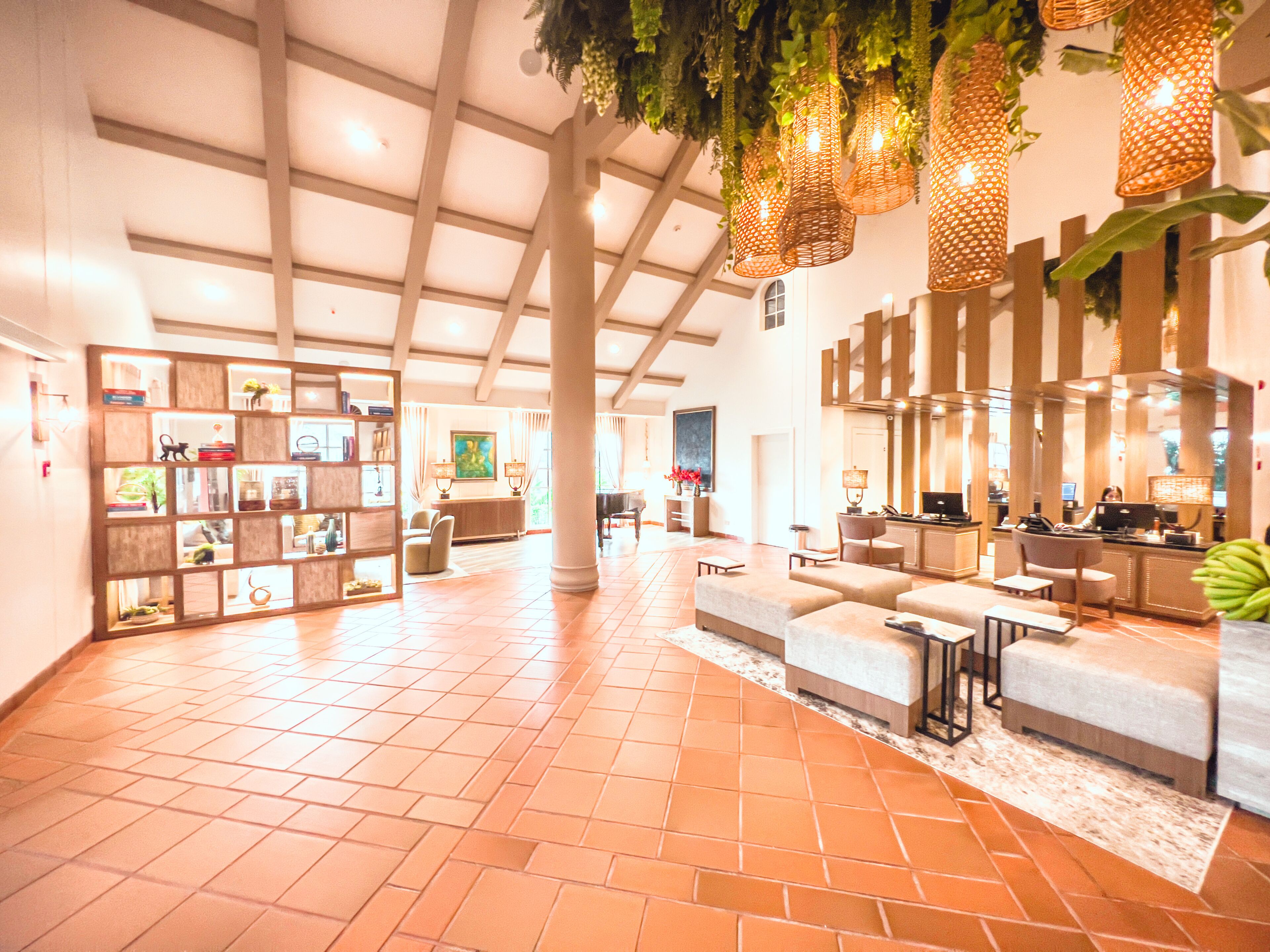 A spacious lobby with a high ceiling, tiled floor, and a seating area with sofas and a coffee table.
